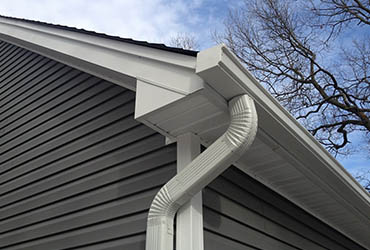 Clearing autumn fall leaves out of residential gutters before winter freeze