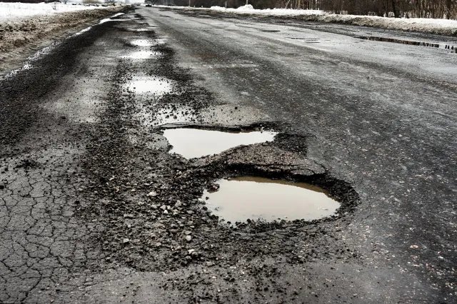 Severe winter roadway pothole and frost heave asphalt damage