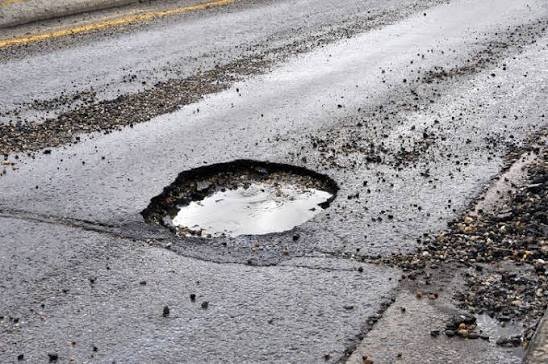 Damaged asphalt highway tire hazard on a winter mountain pass